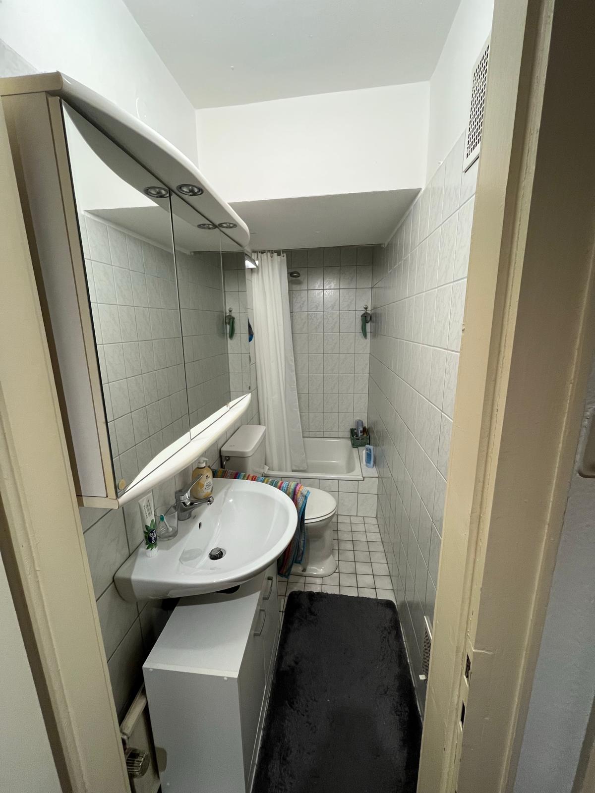 Gefliestes Badezimmer mit Waschbecken, Spiegelschrank, WC und Badewanne in der Wohnung in Aachen