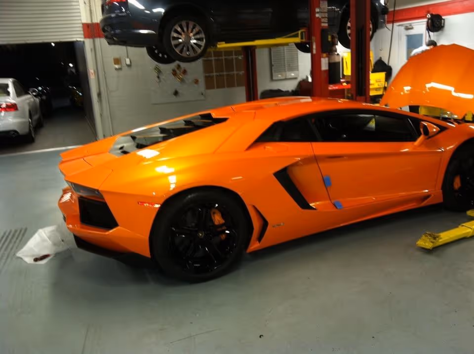 Bright orange Lamborghini in auto repair shop with car lift