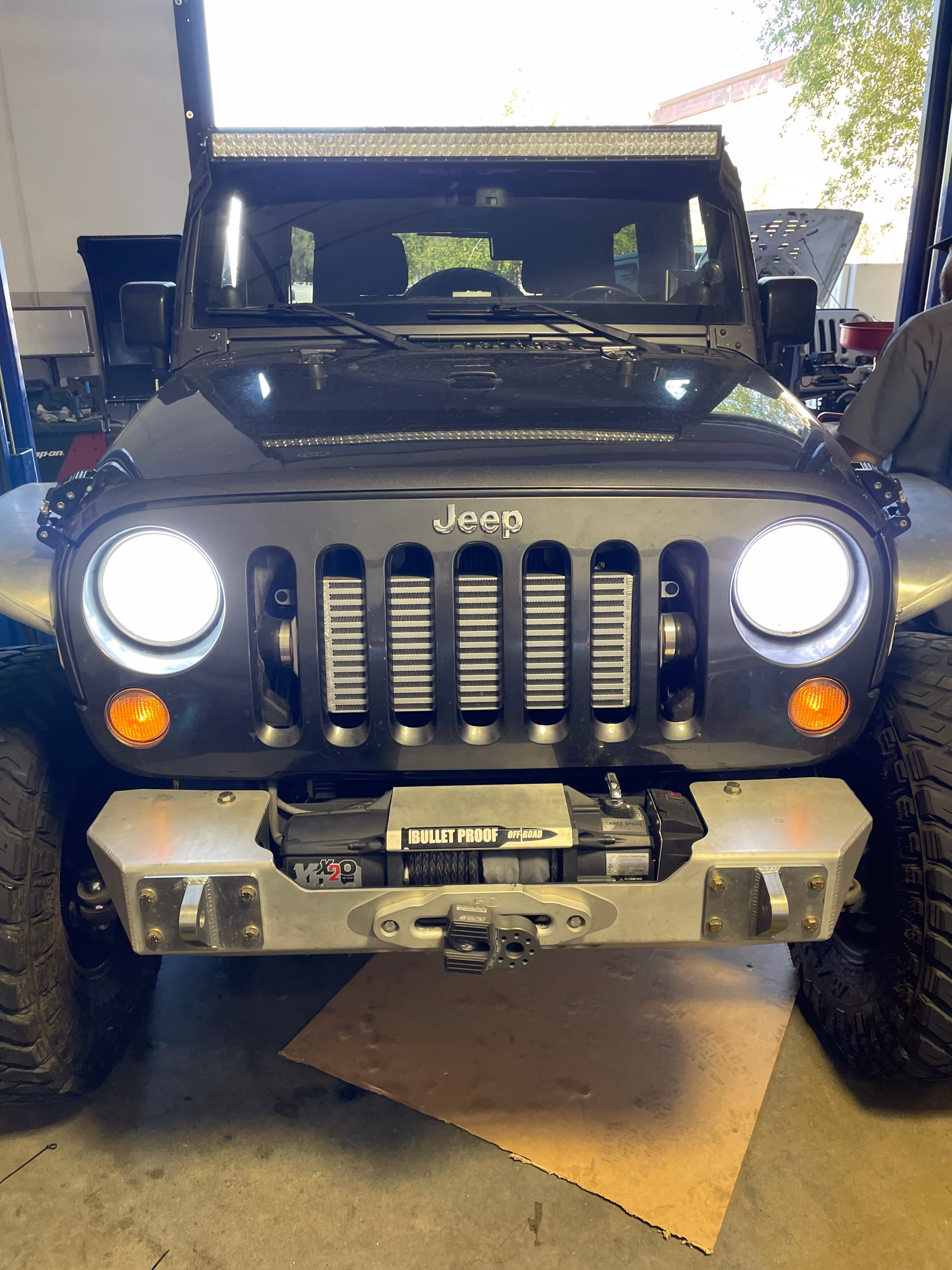 Black Jeep Wrangler with off-road winch in automotive workshop