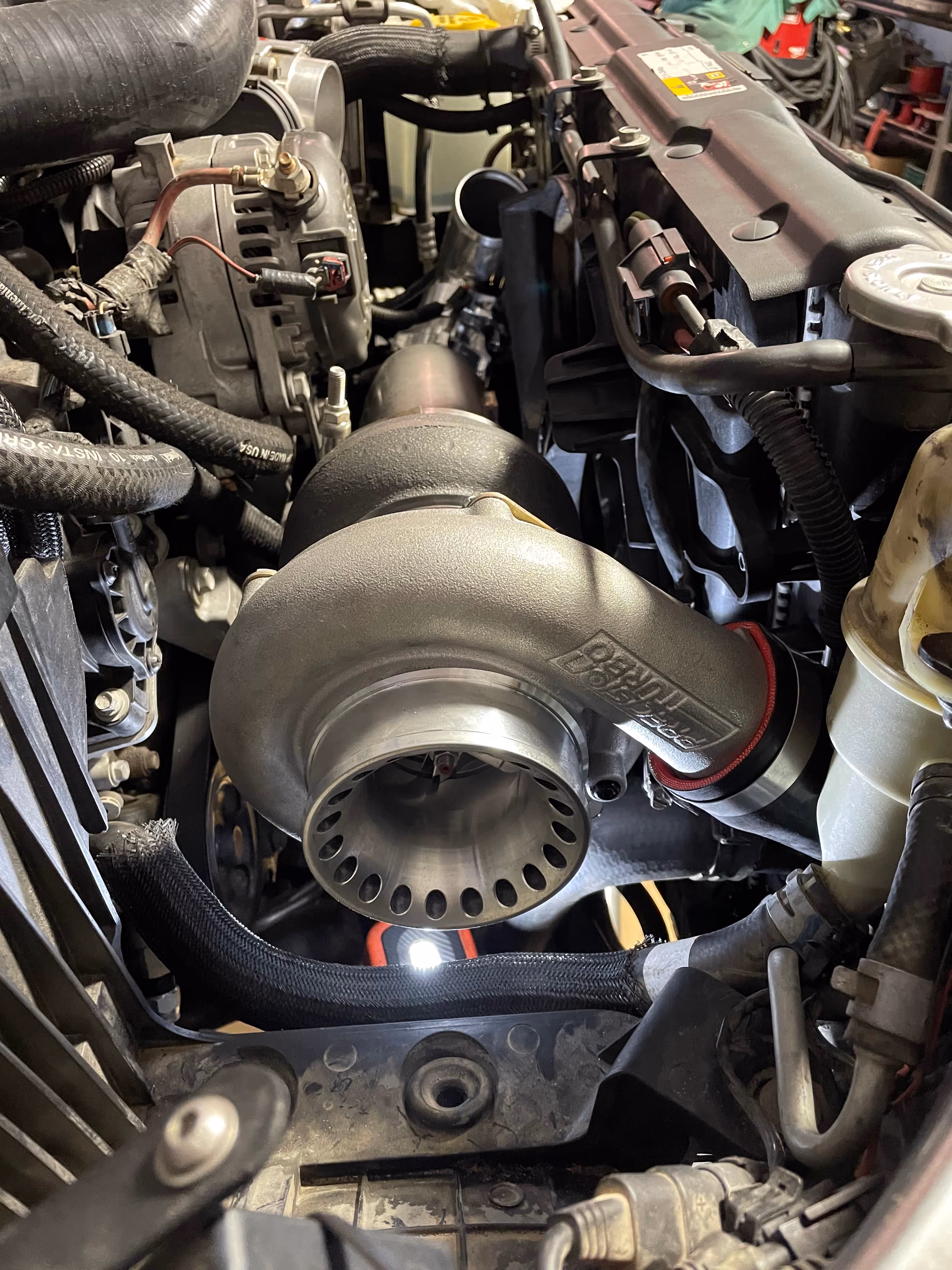 Close-up of a turbocharger installed in a complex car engine bay