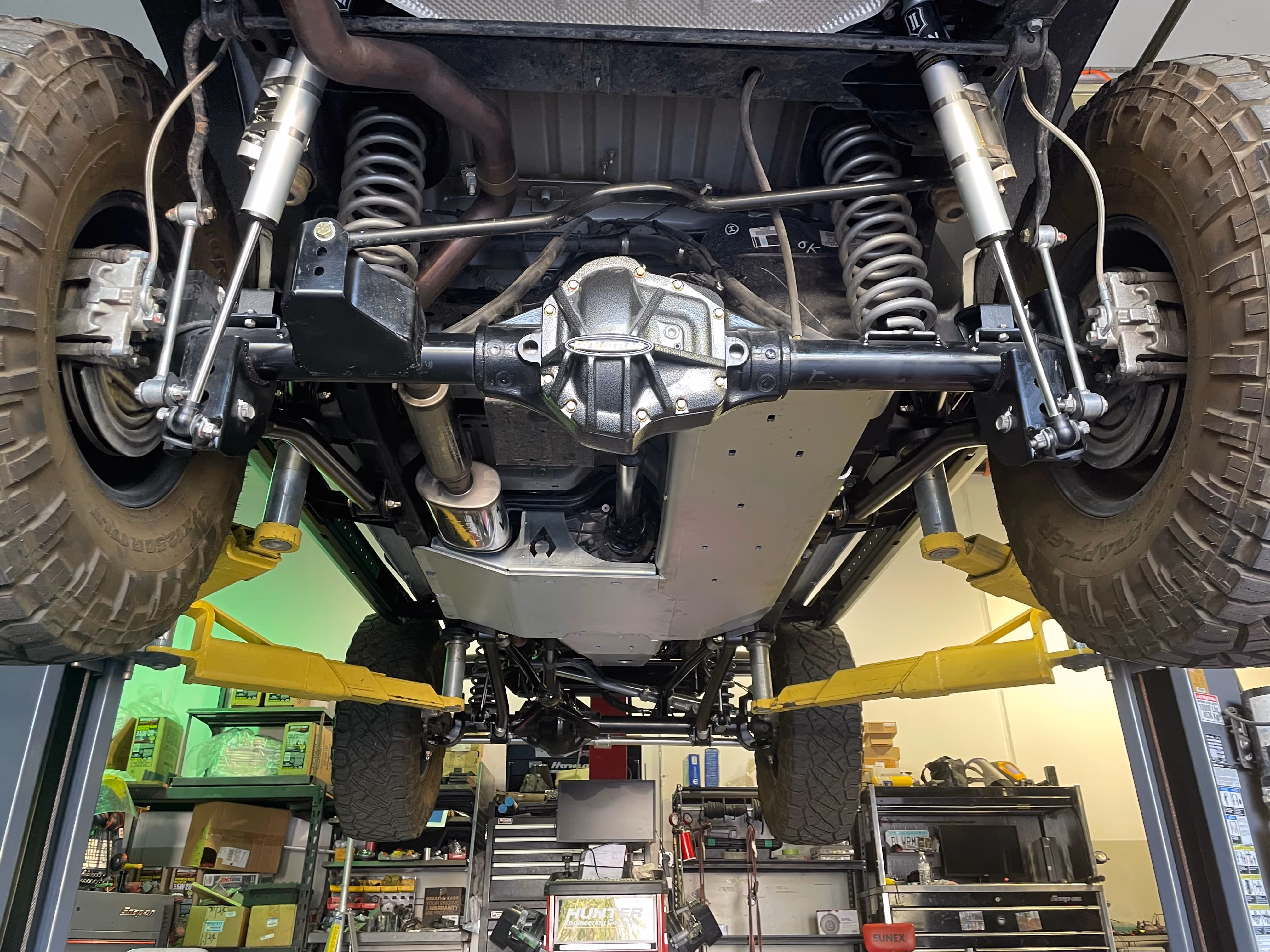 Undercarriage of off-road vehicle showing suspension, axle, and rugged tire setup