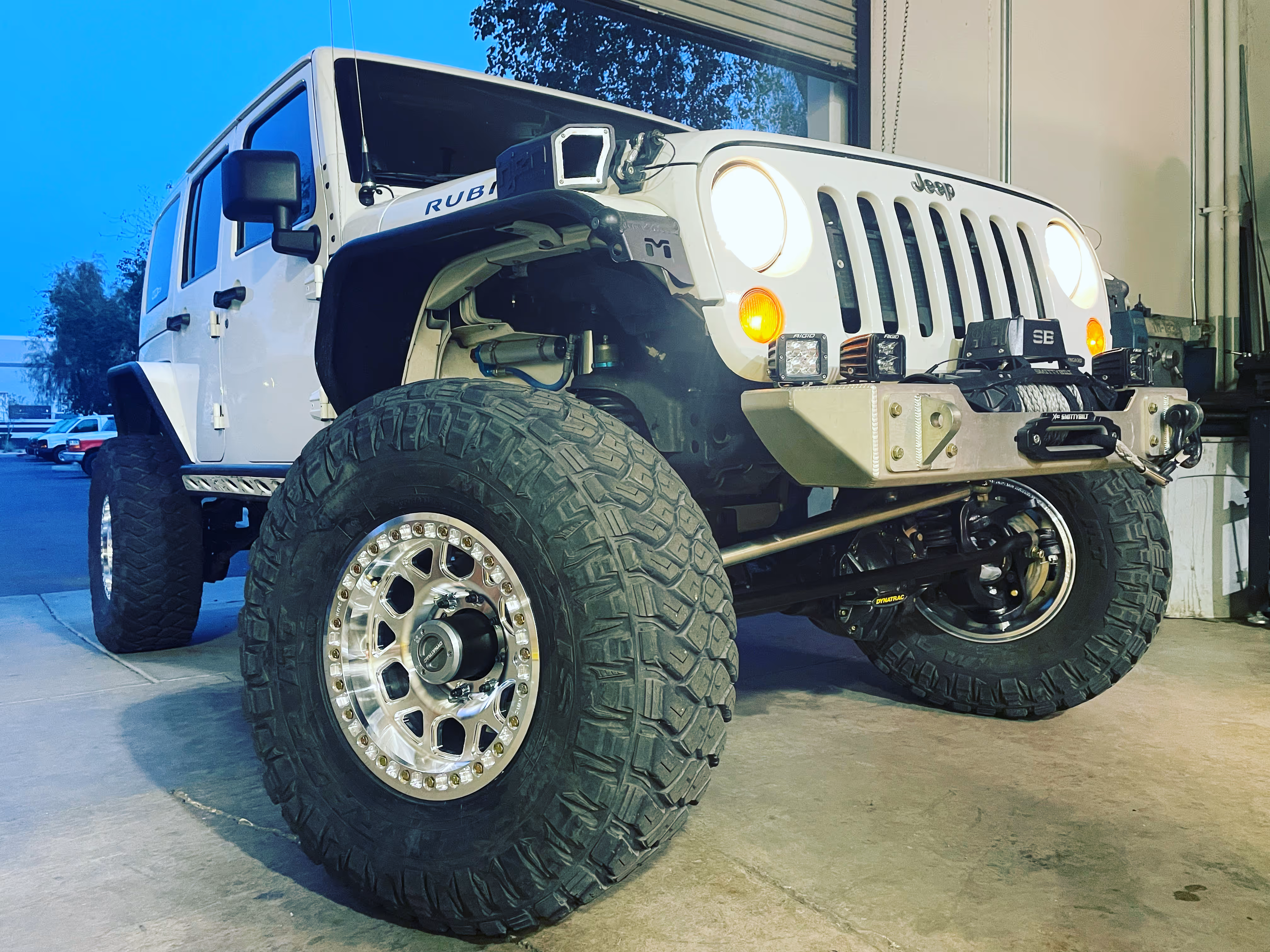 White Jeep Wrangler Rubicon with oversized off-road tires and custom bumper