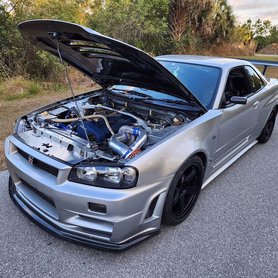 Silver Nissan Skyline GT-R with open hood showing turbocharged engine bay