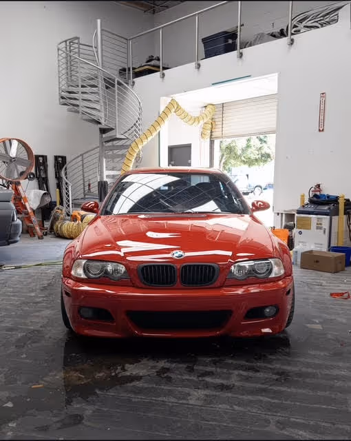Red BMW sports car parked inside a garage with spiral staircase