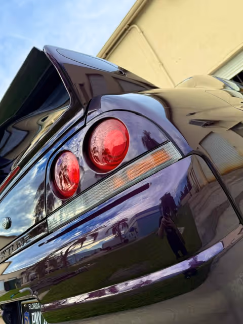 Glossy dark sports car rear taillight with reflective surface and red lens