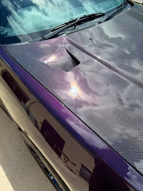 Carbon fiber car hood with purple accent and reflective light highlights