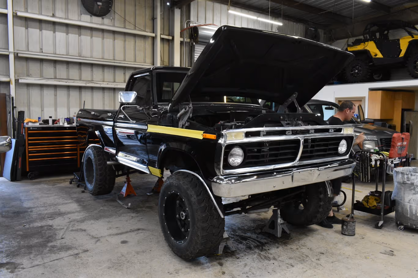 Black vintage Ford truck raised on jack in auto repair workshop