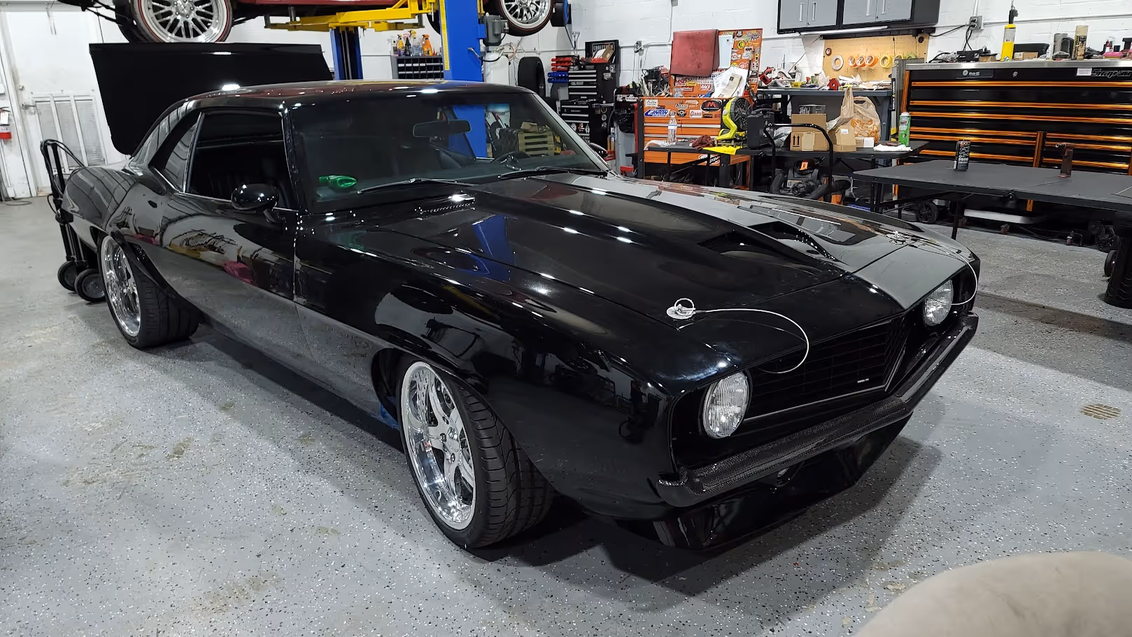 Sleek black classic muscle car with chrome wheels in auto workshop