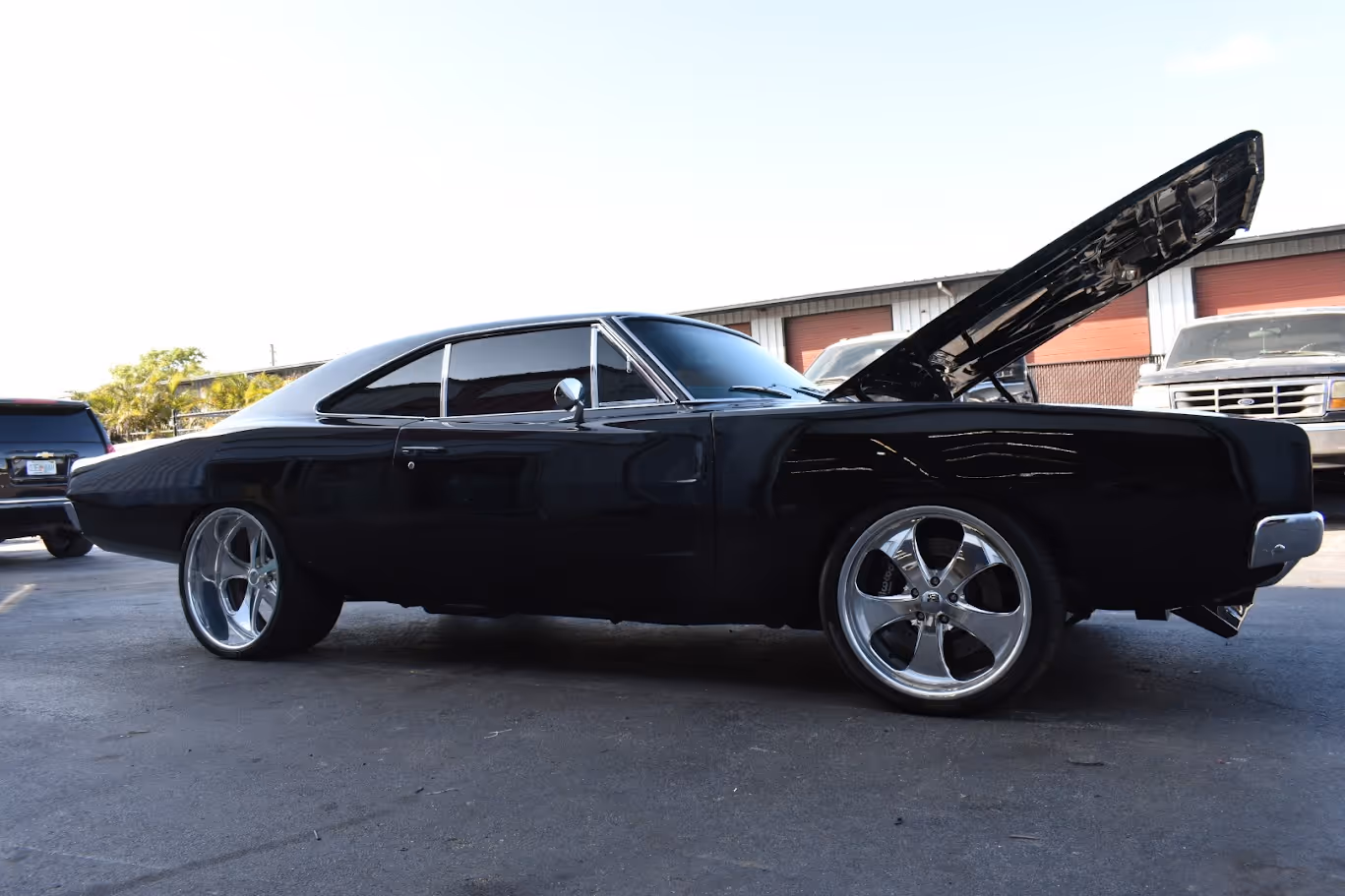 Black classic muscle car with open hood and custom chrome wheels