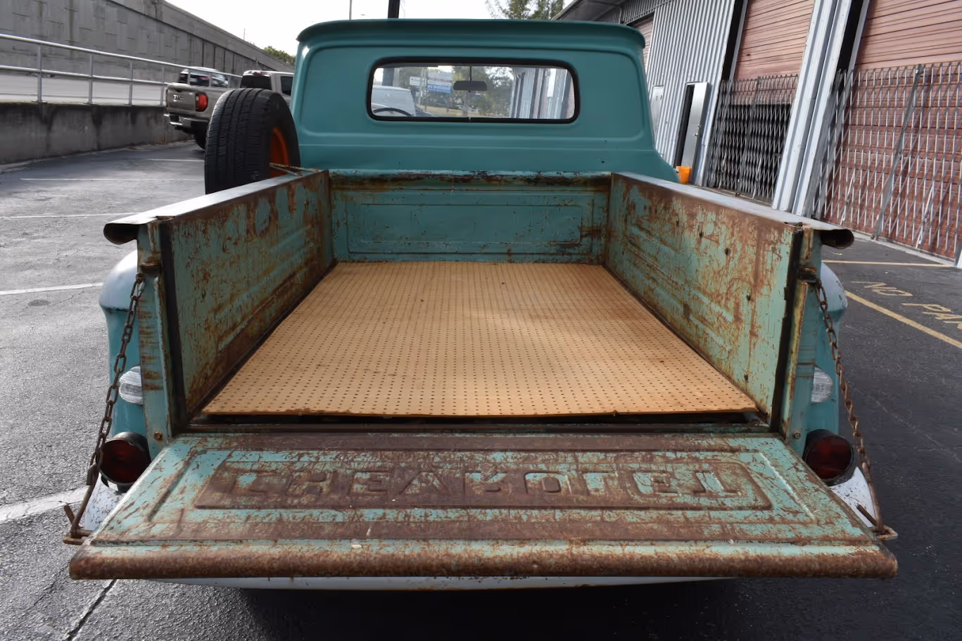 Vintage teal pickup truck with rusty bed and wooden floor