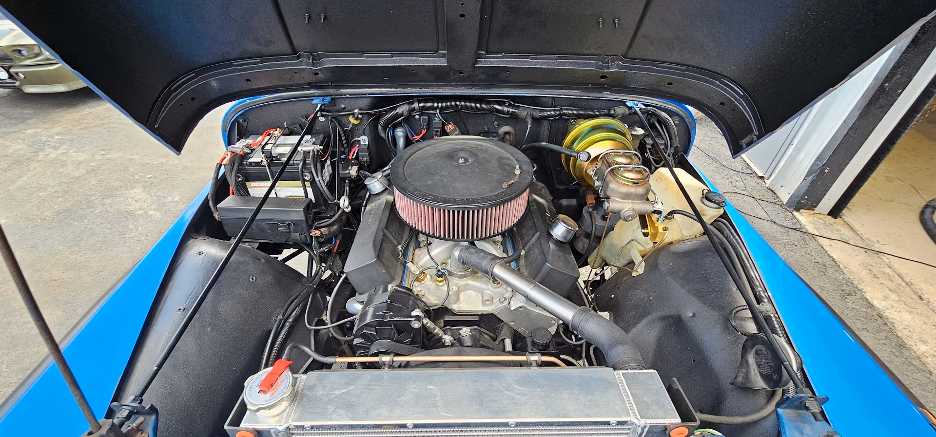Classic car engine bay with large air filter and blue surrounding
