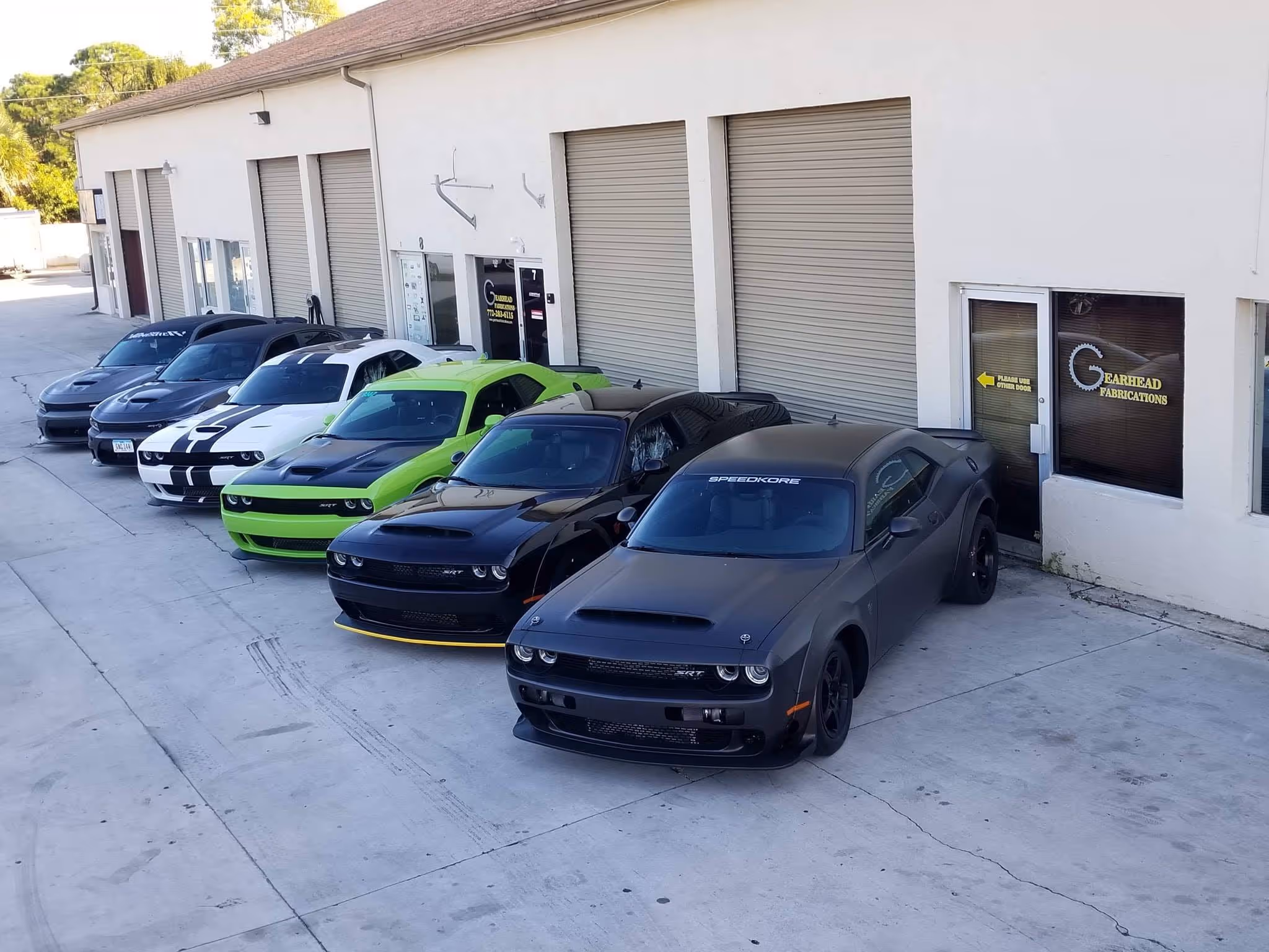 Multiple Dodge Challengers in different colors parked outside garage