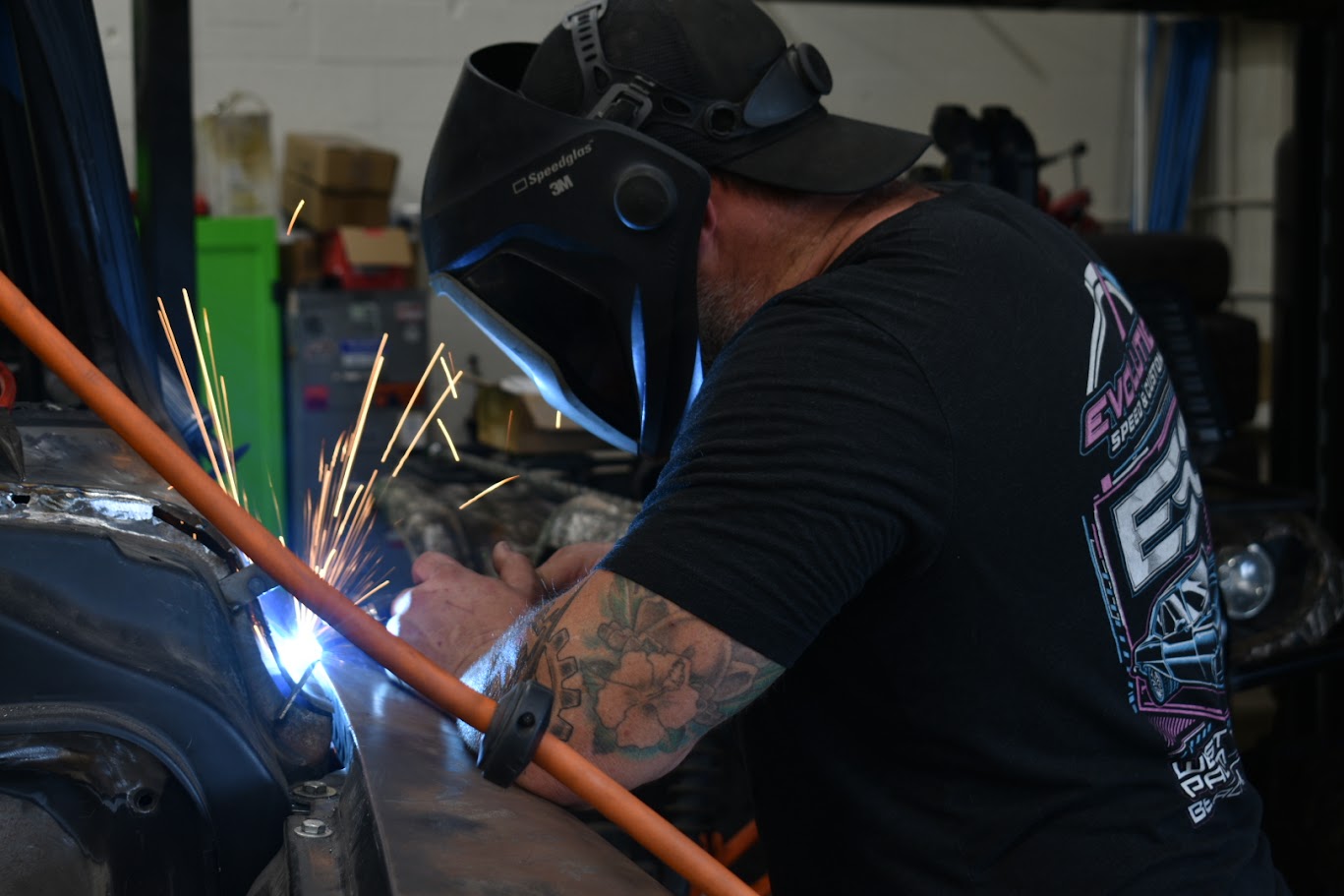 Welder with protective mask working, sparks flying during metal fabrication