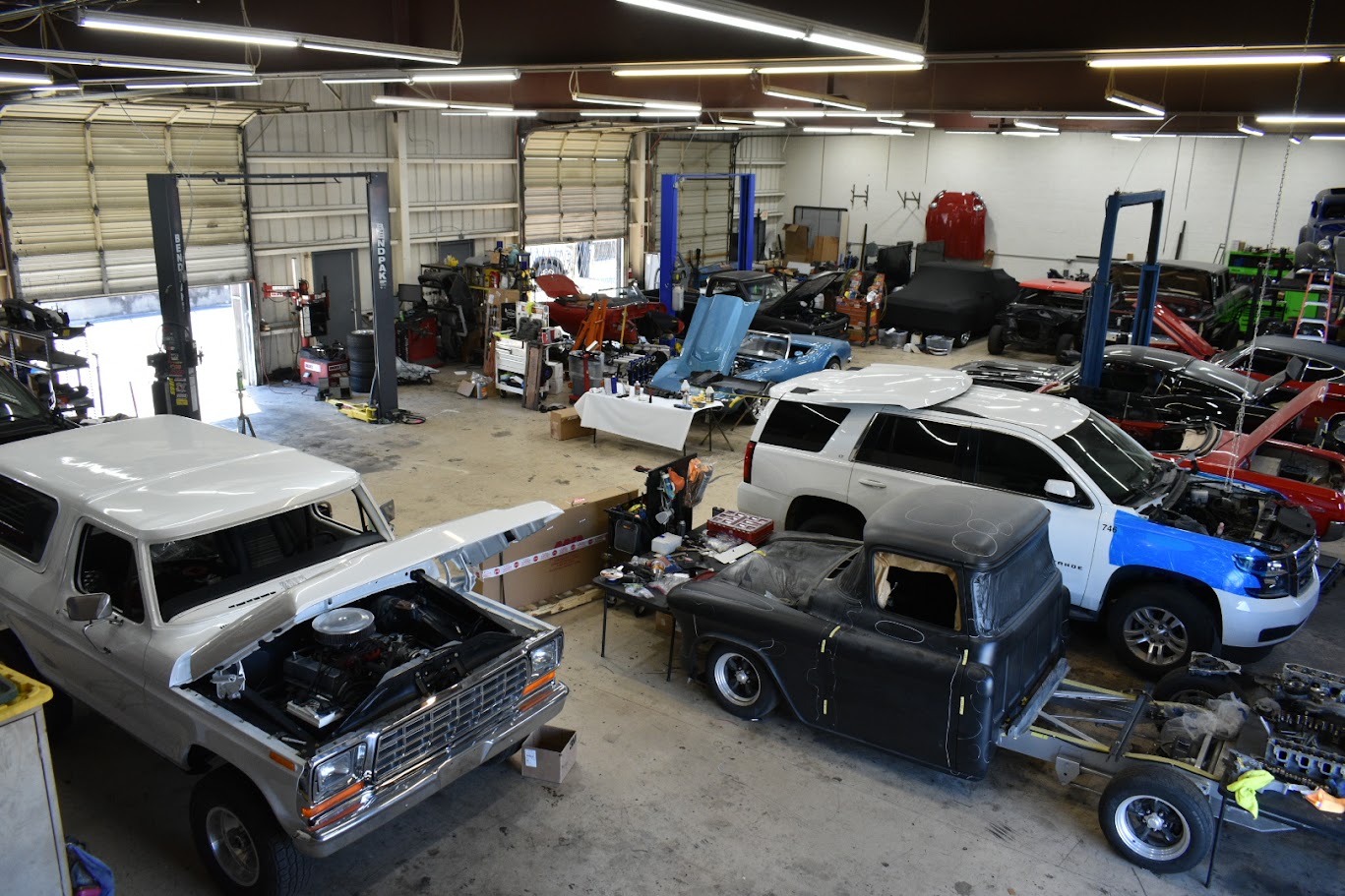 Auto repair shop with multiple vehicles in various stages of restoration