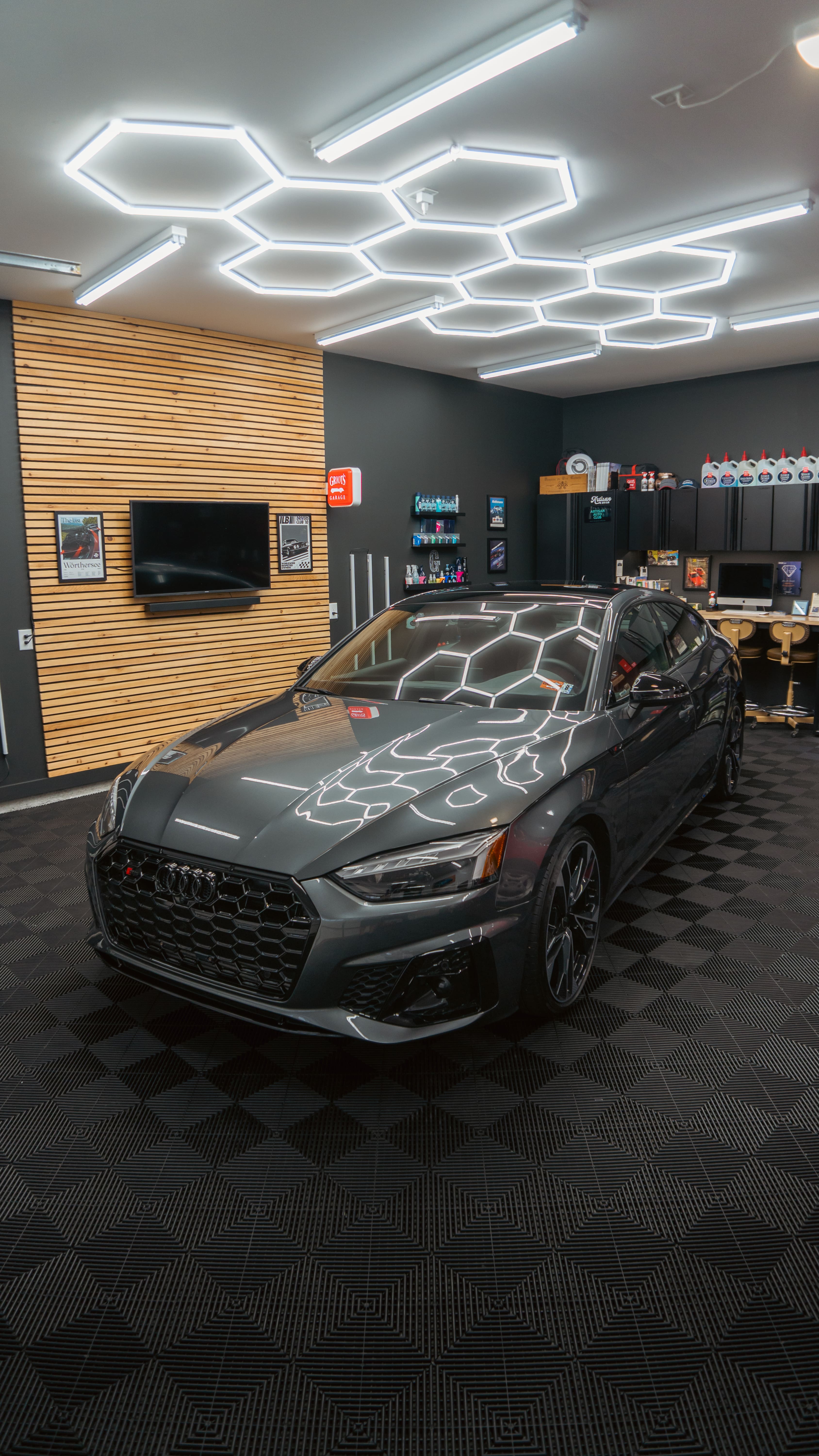 Gray Audi sports car parked in modern showroom with hexagonal lighting