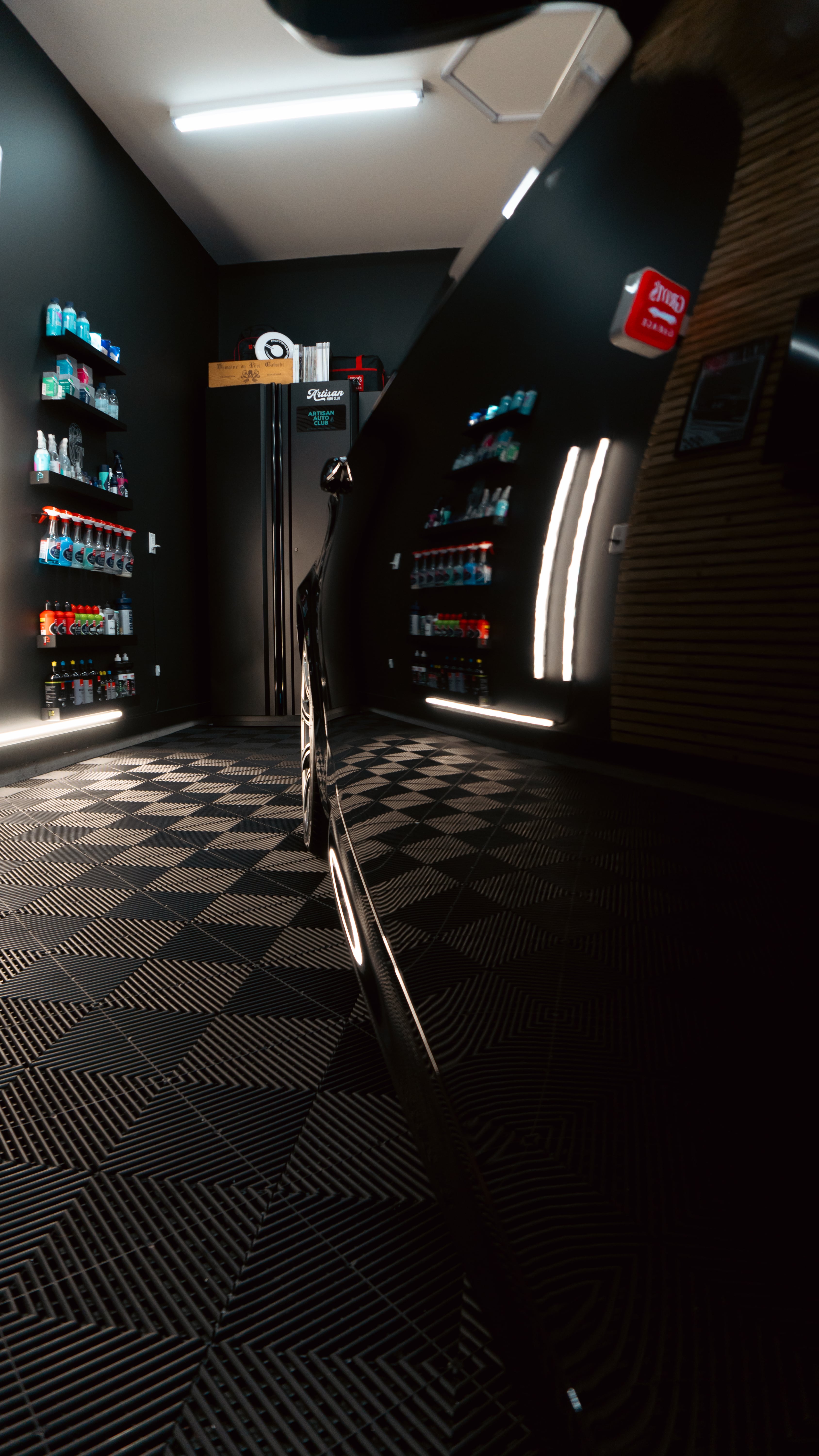 Dark room with shelves of colorful bottles and geometric floor pattern