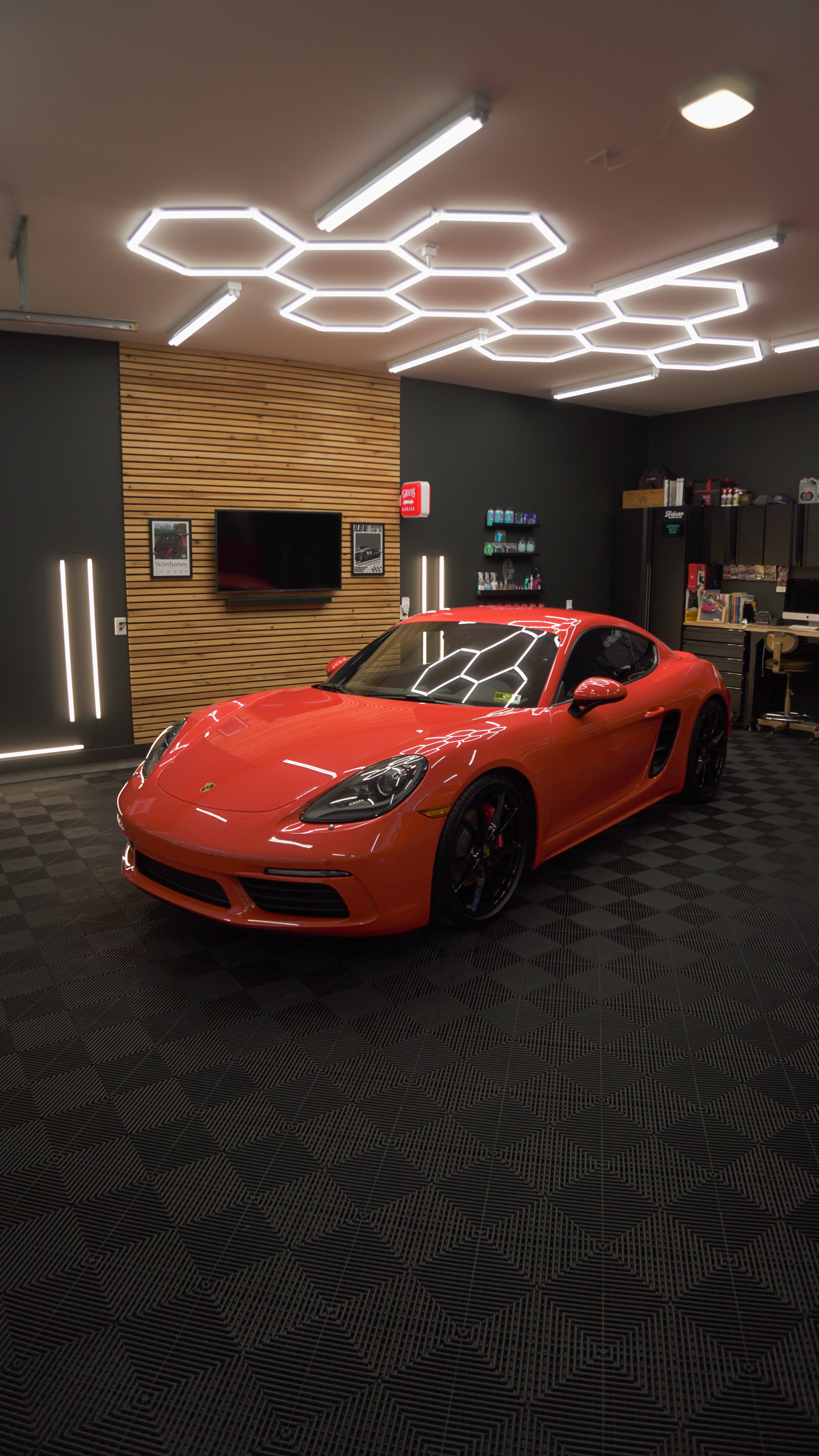 Bright red sports car parked in modern showroom with hexagonal ceiling lights