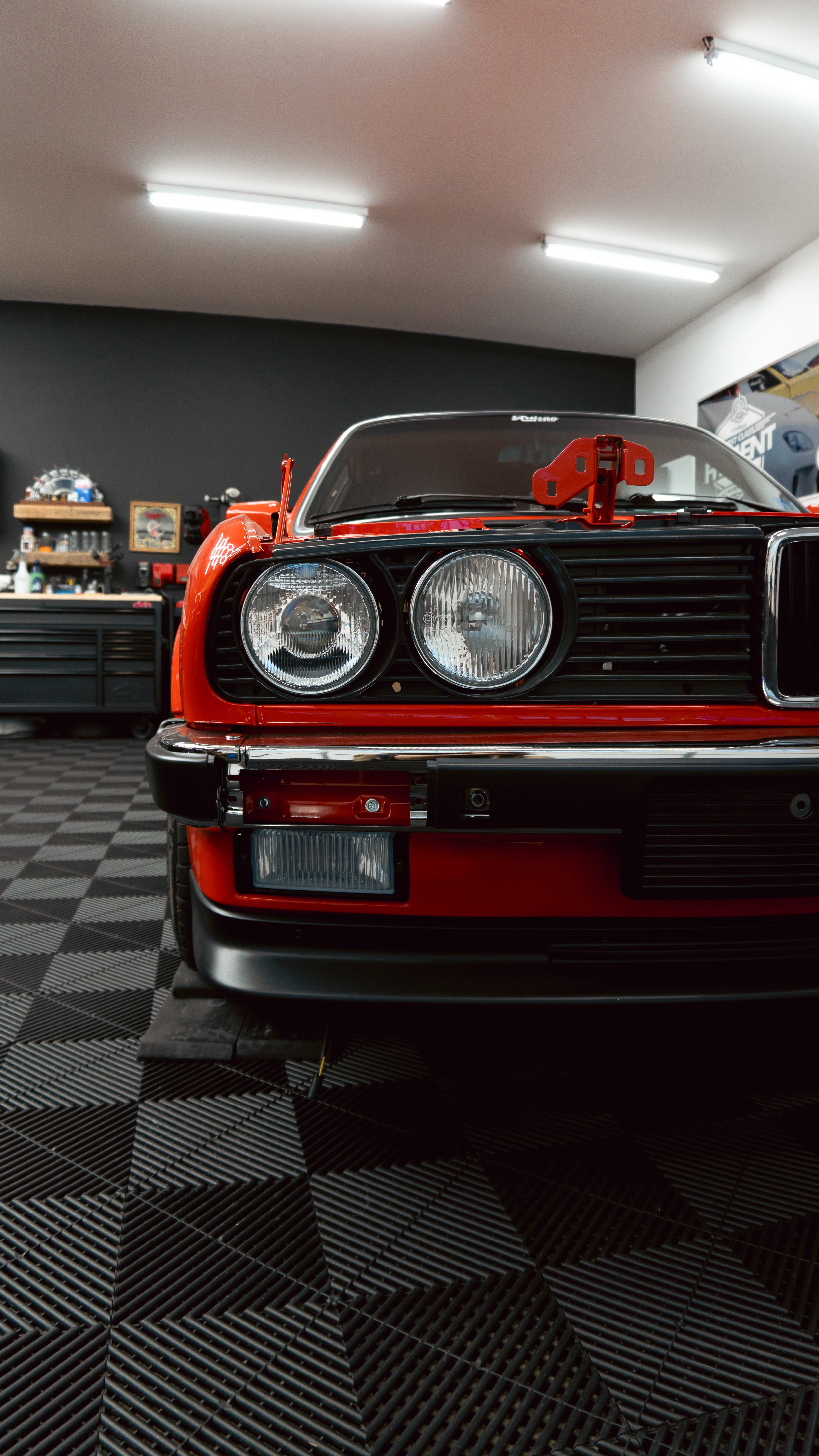 Red vintage BMW in workshop with detailed front headlight and grill view