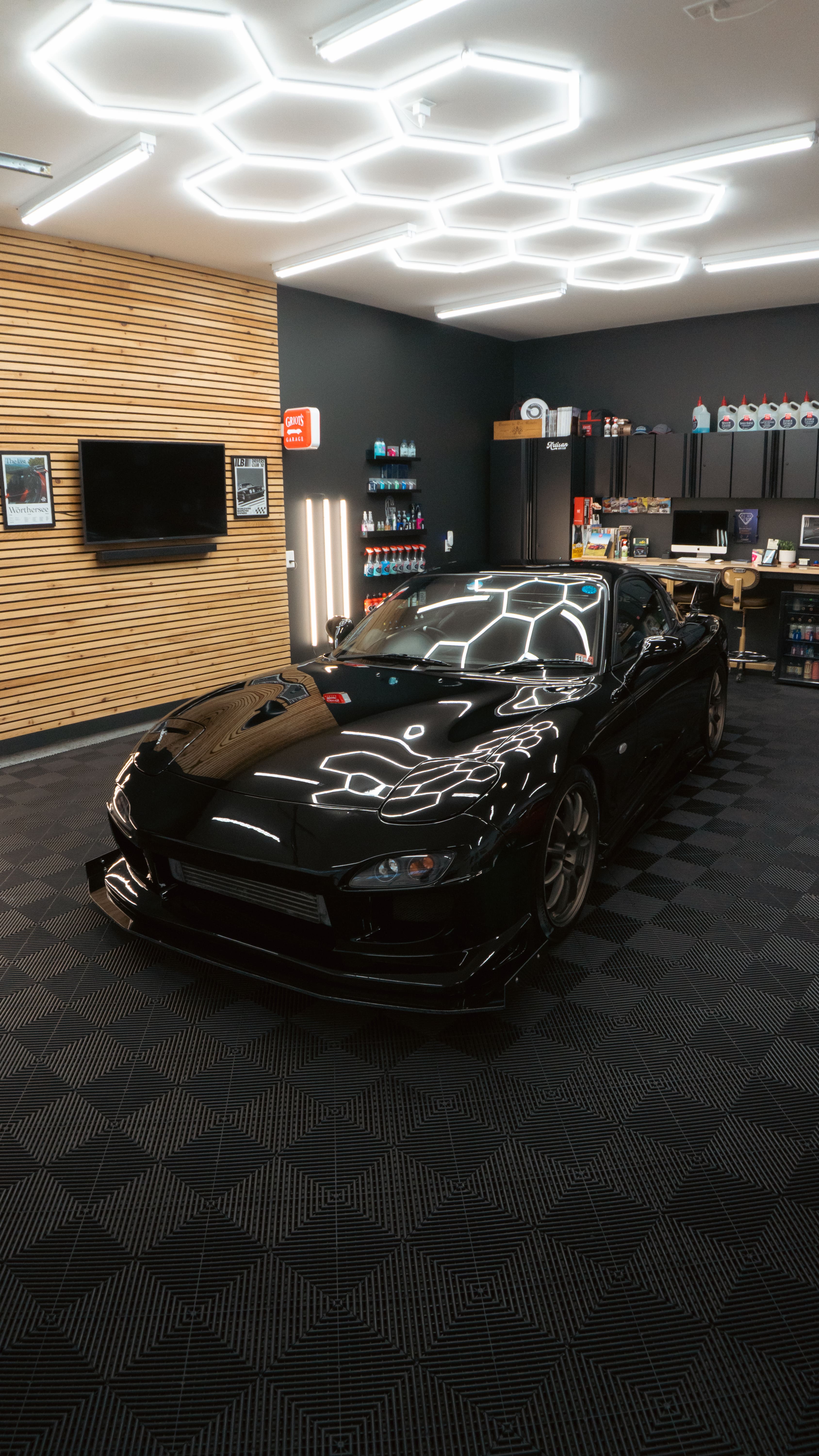 Black sports car with reflective lines in modern automotive workshop