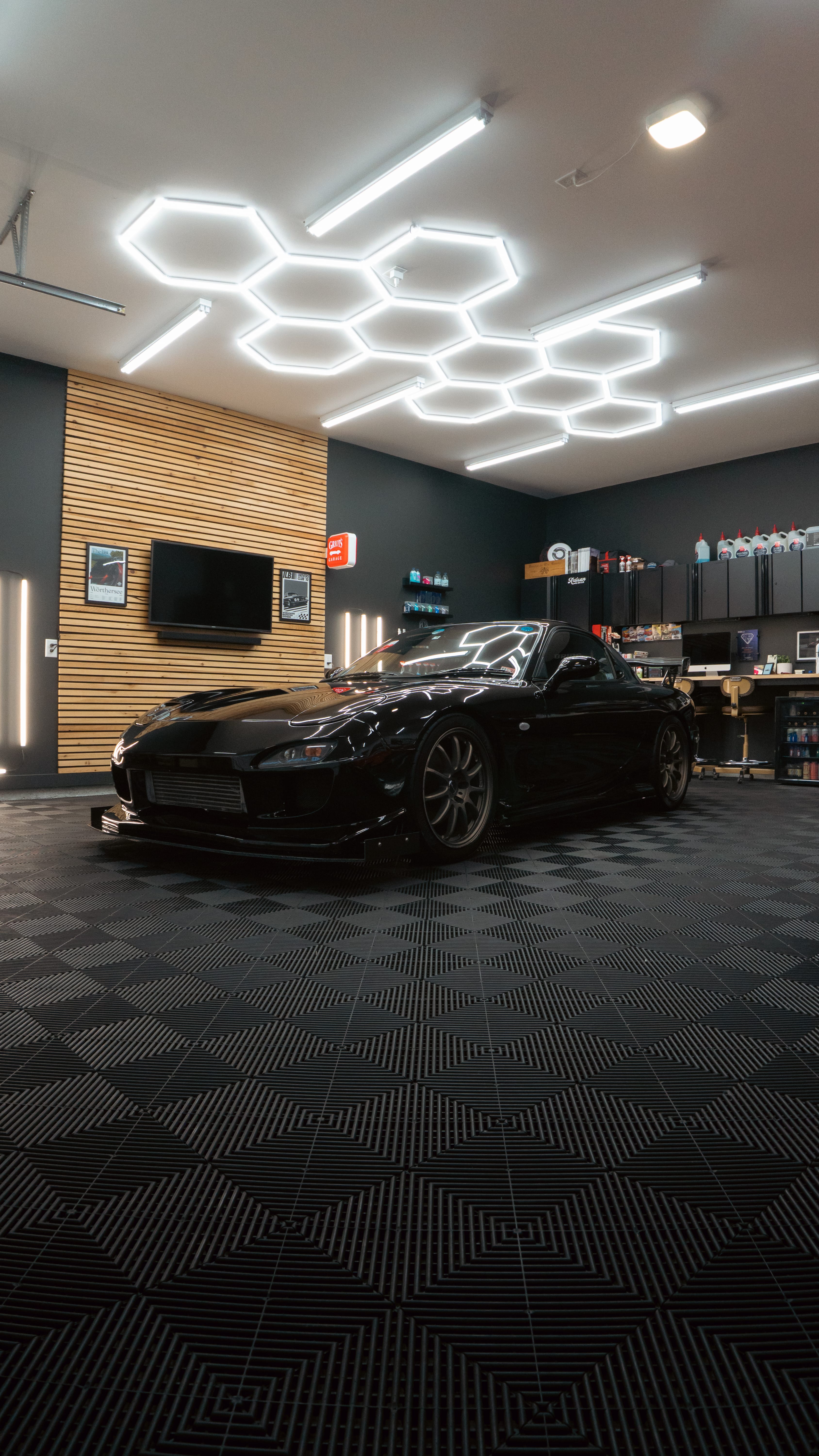 Black sports car in modern garage with hexagonal LED ceiling lights
