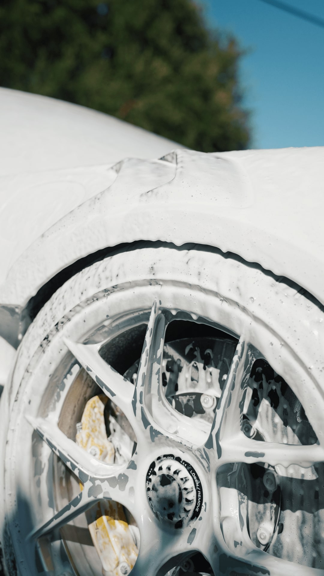 Soapy car wheel covered in white foam during a car wash