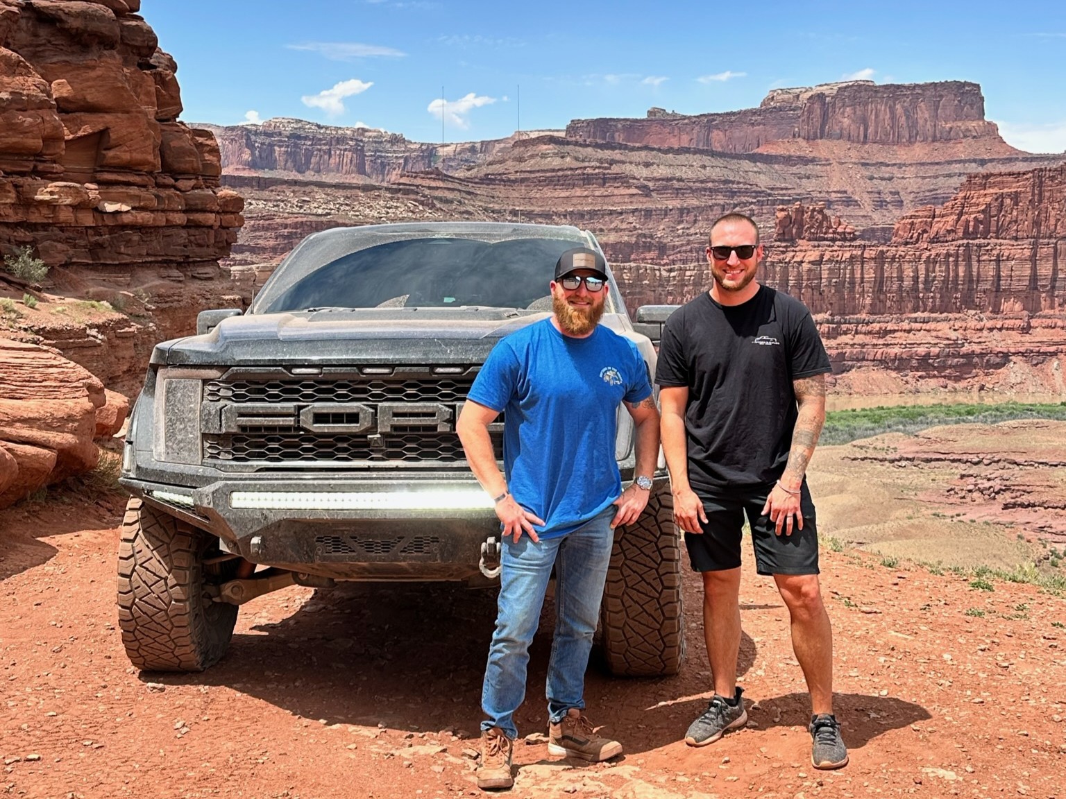 Two men posing with truck in red rock canyon landscape