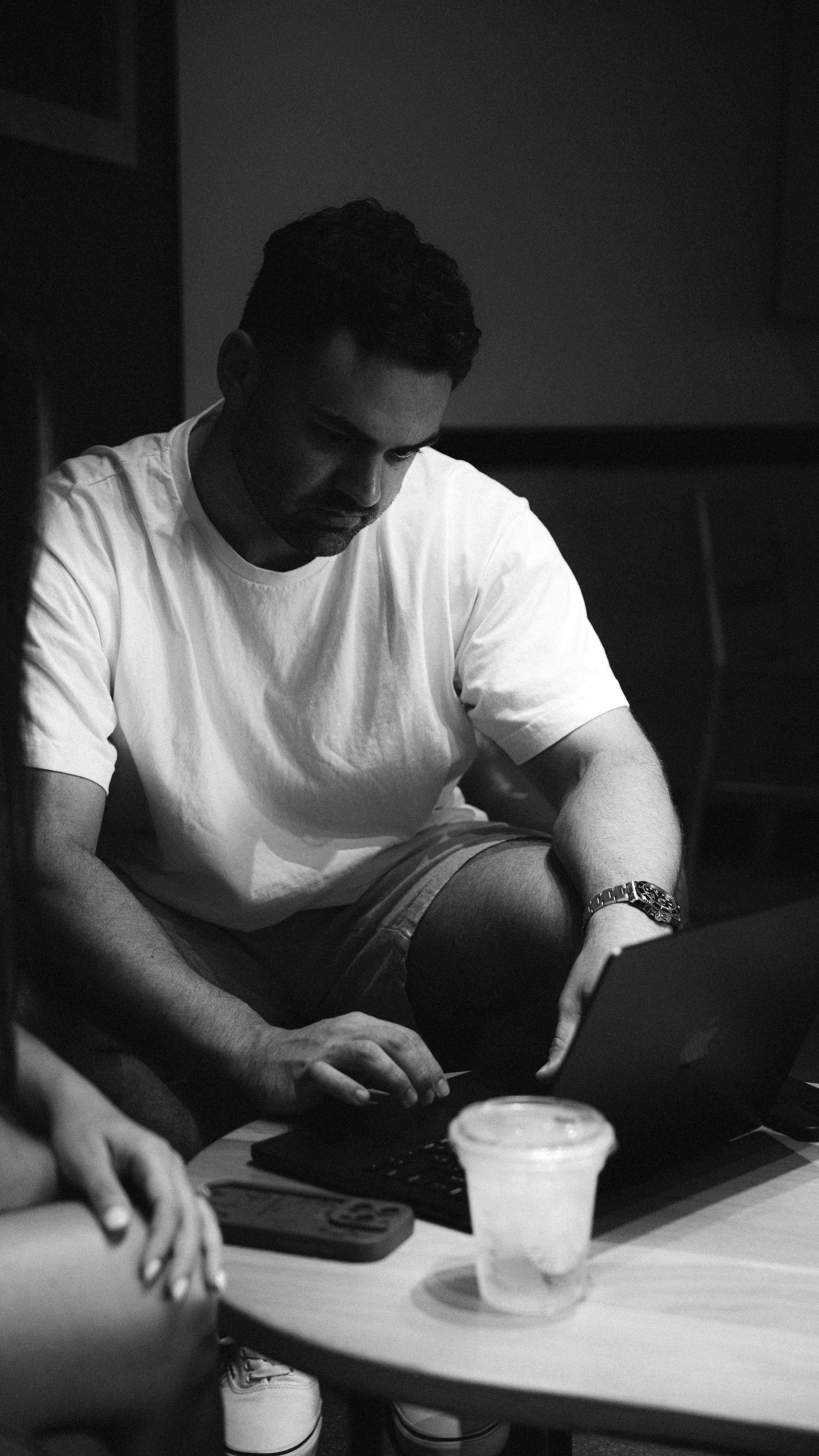 Person working on laptop with cold drink in black and white