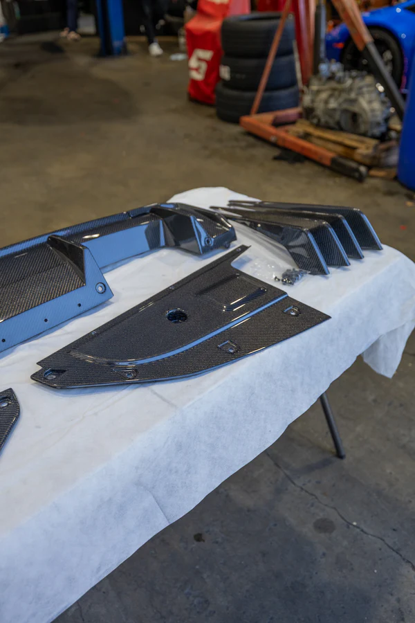 Carbon fiber automotive body panel laid out on white cloth in workshop