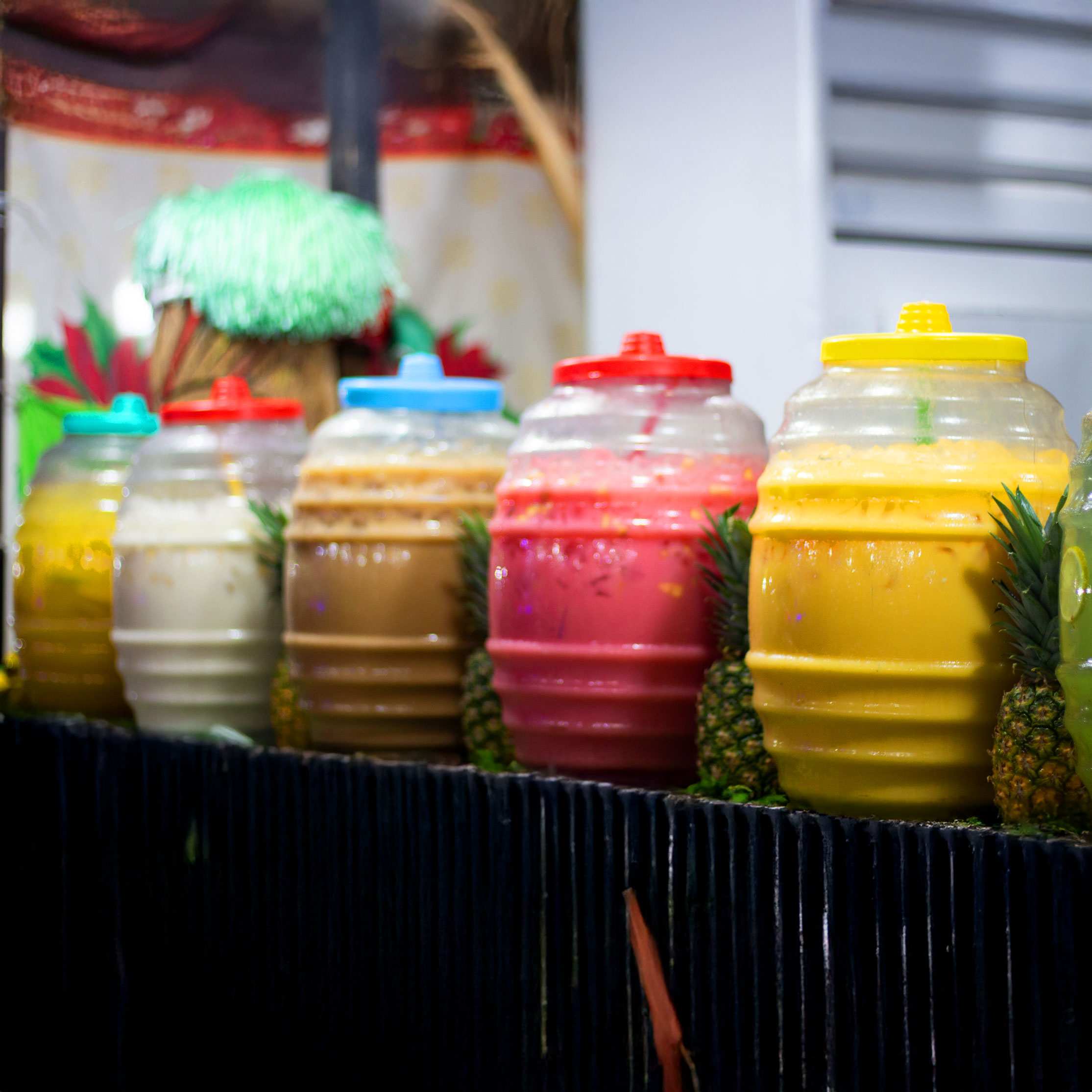 A row of glass pitchers filled with colorful aguas frescas.