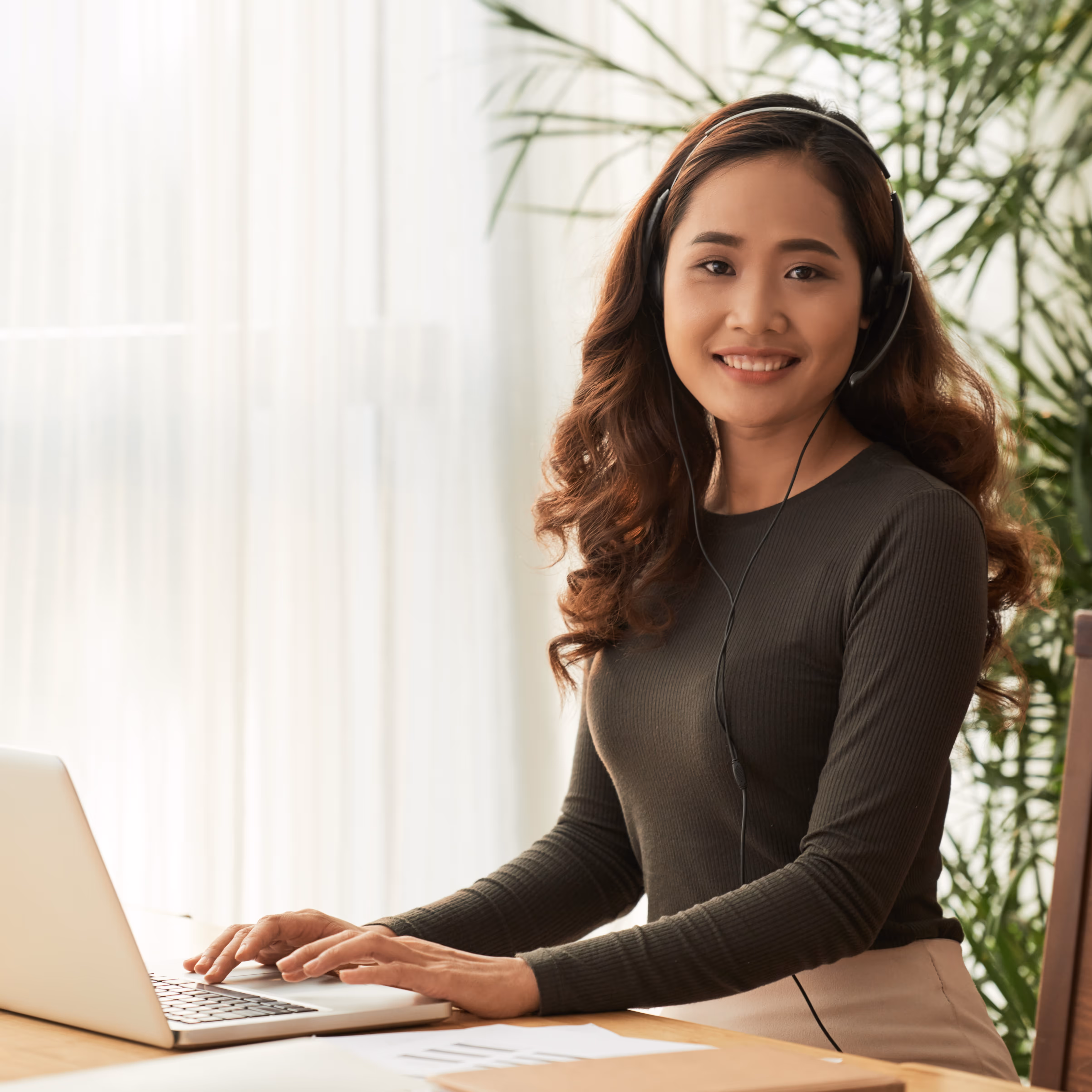 A young woman smiling while working  on her laptop.