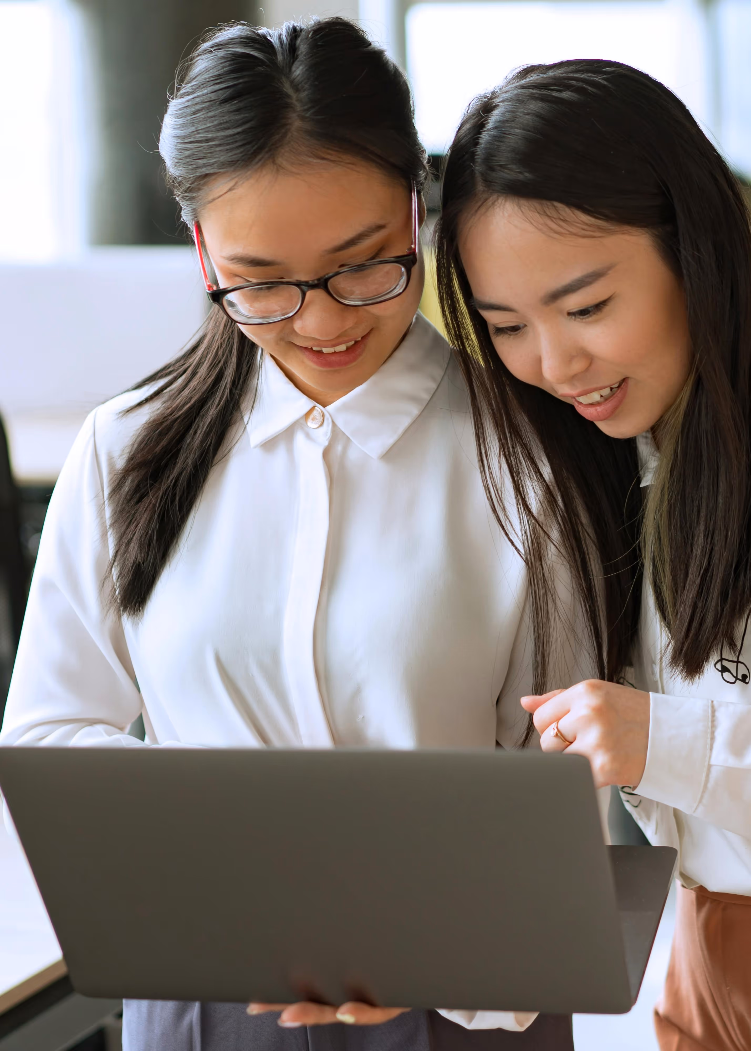 A closeup of two women working together in a corporate setting.