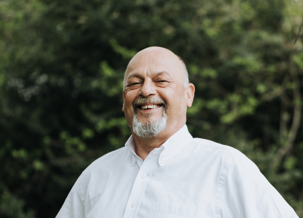image of man with facial hair, outdoors with a big smile