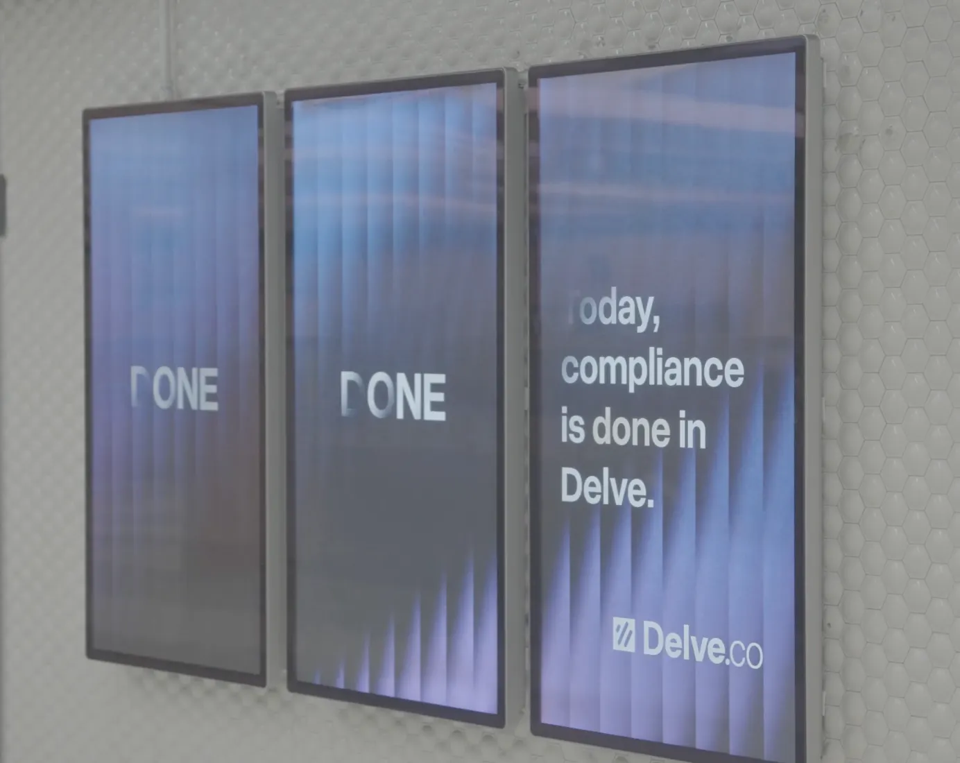 Three vertical digital screens on a wall display a message: 'Today, compliance is done in Delve.' with the Delve.co logo.