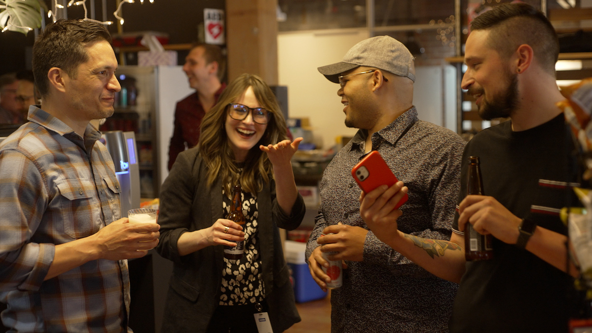 A group of professionals in a casual setting with drinks laughing and socializing