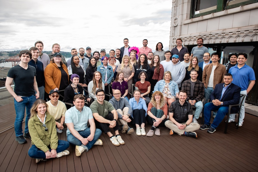 A group image of about 50 smiling professional-looking people on a rooftop in downtown Seattle. 