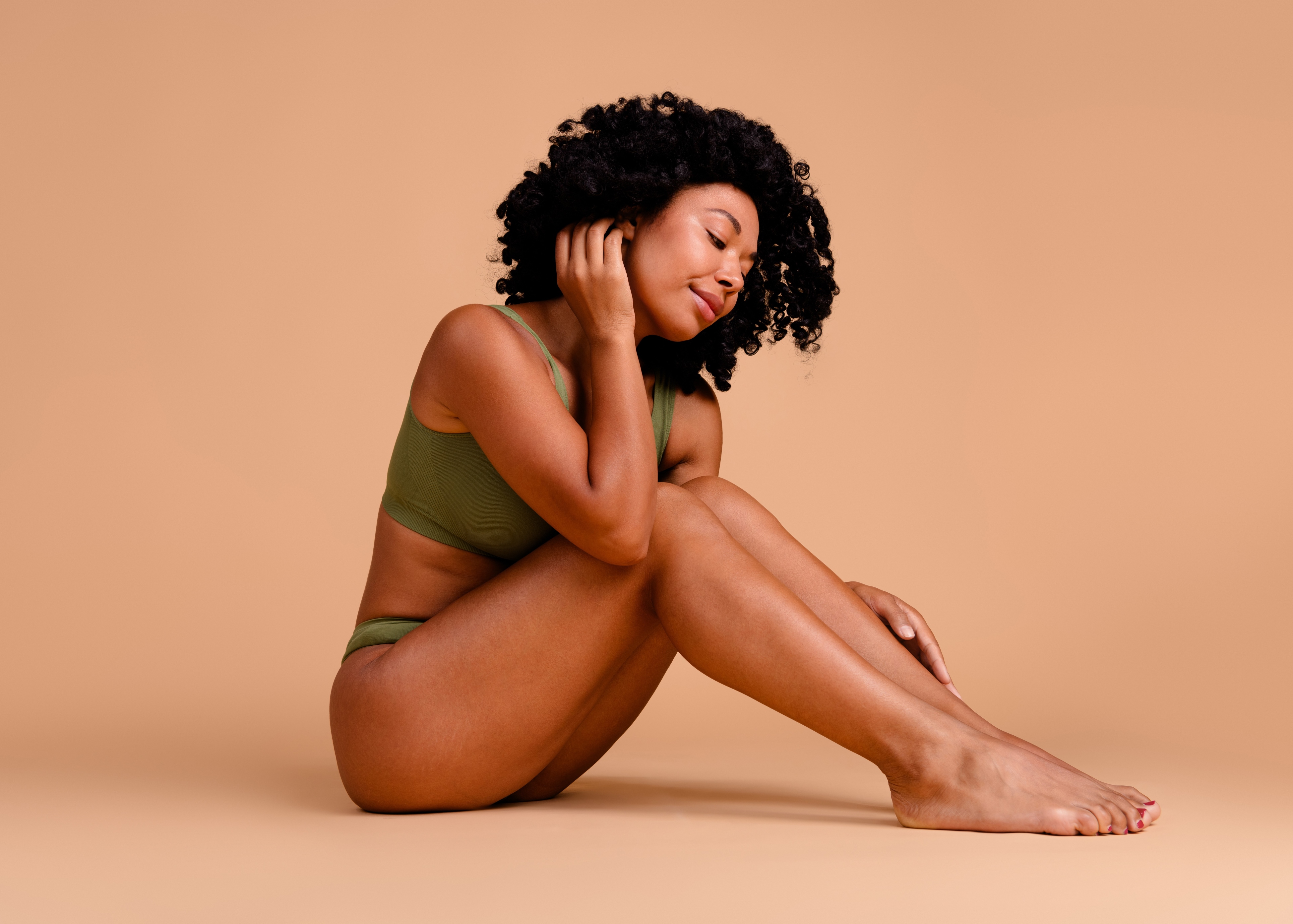 A woman sitting on the ground with her legs crossed.