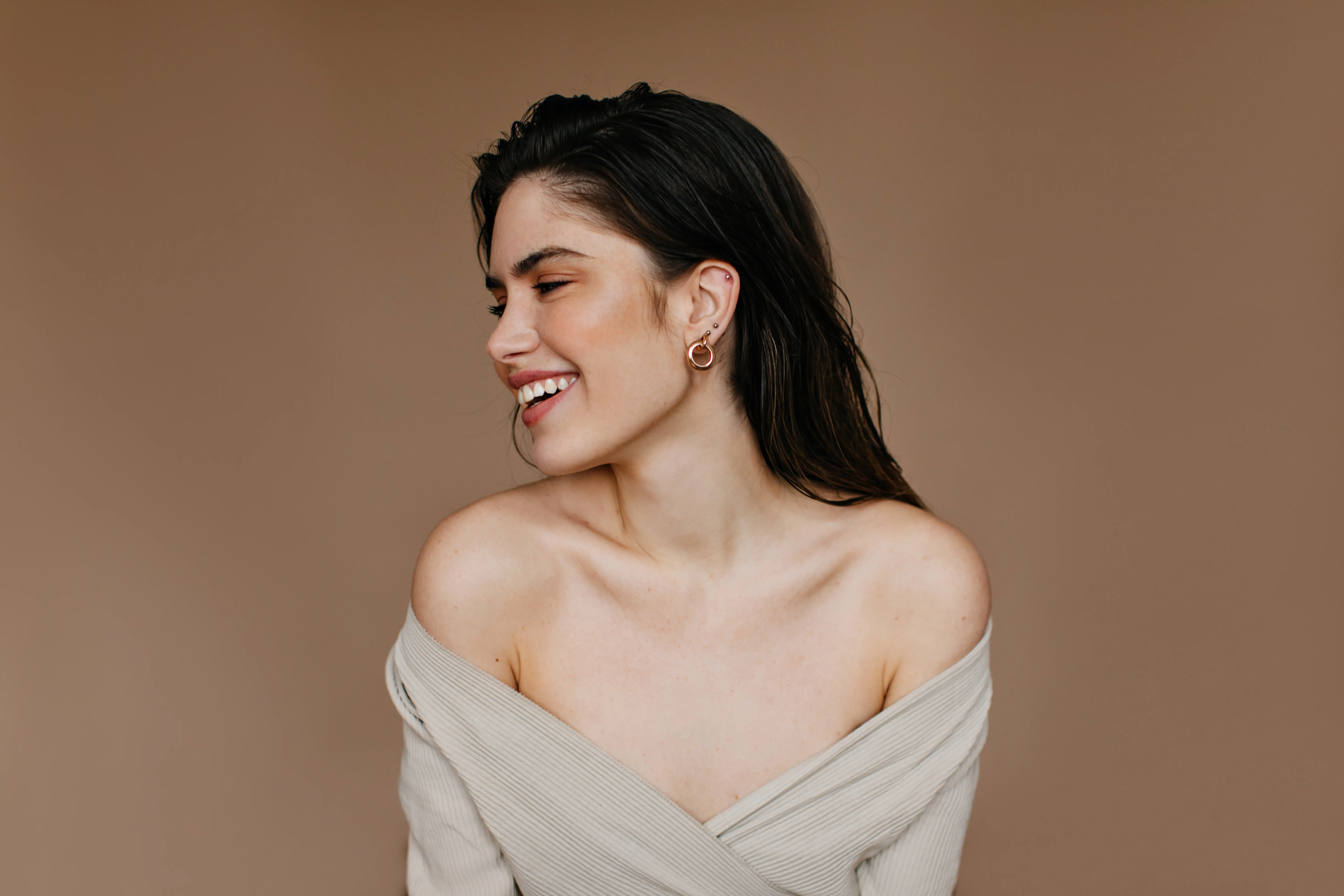 A woman in a white dress smiling and looking off to the side.
