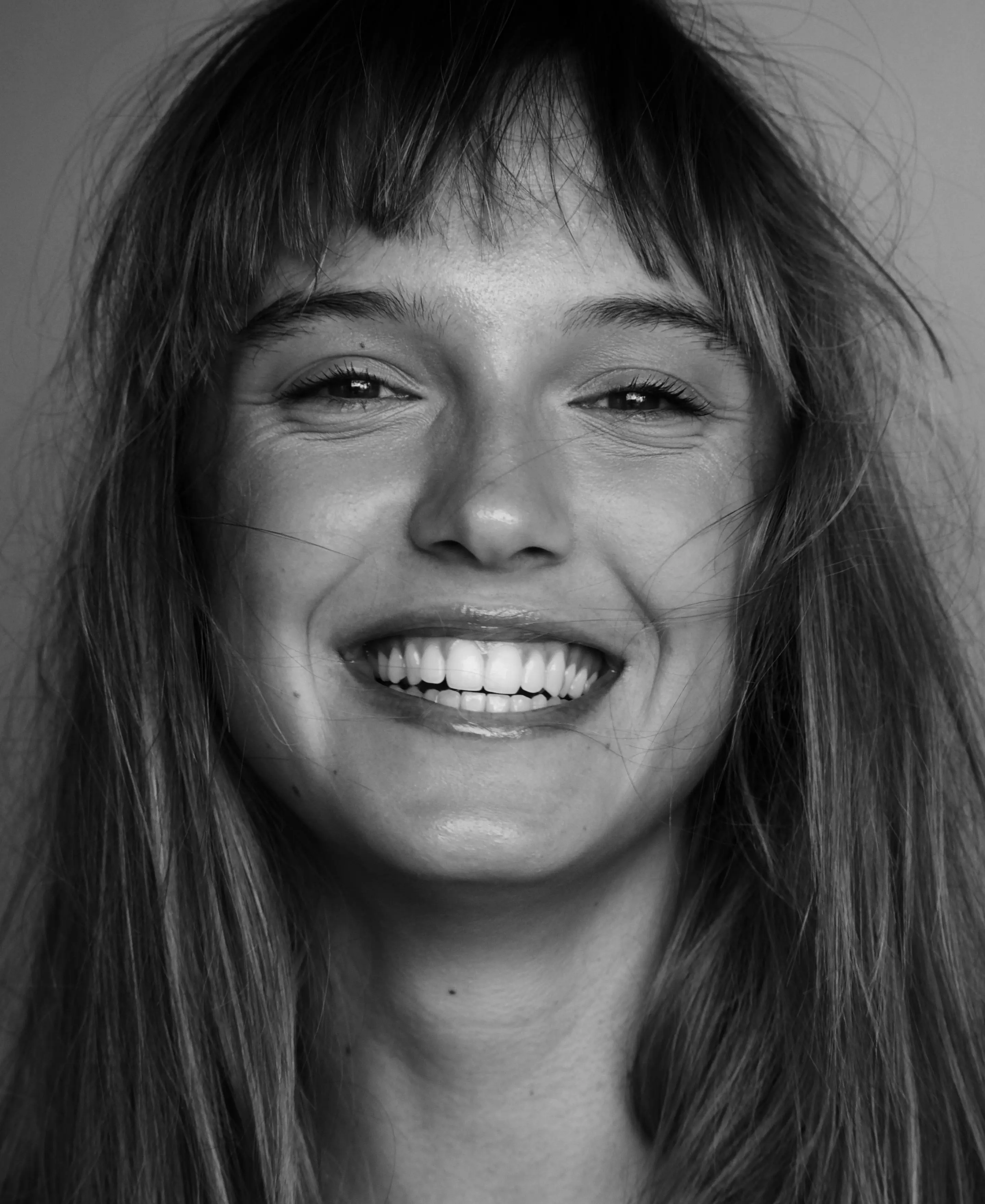 A black and white photo of a smiling woman.