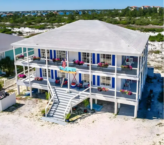 Modern two-story house with a black and white exterior, a driveway with a parked silver SUV, surrounding greenery, and a fenced garden.