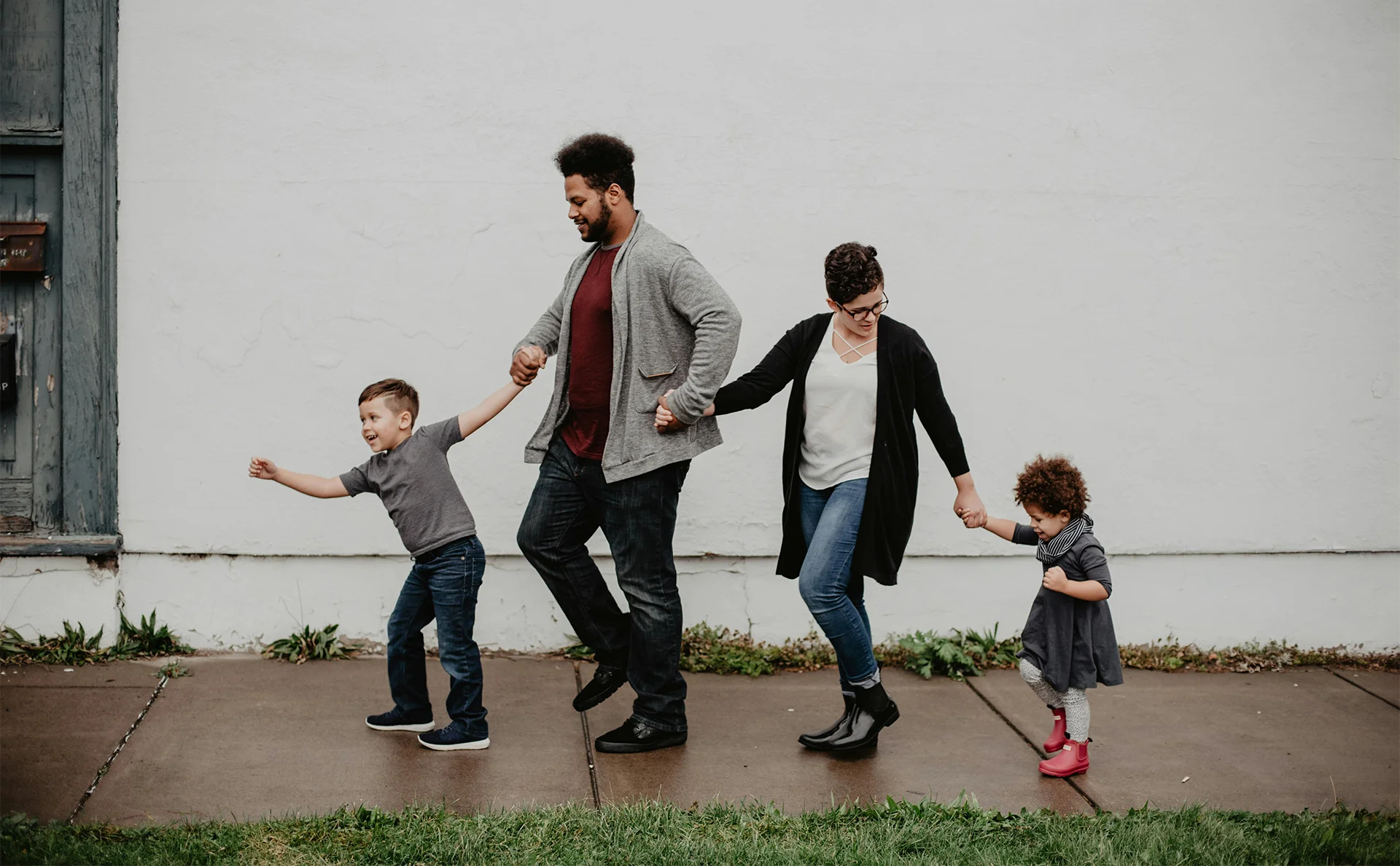 Young family walking along sidewalk happily