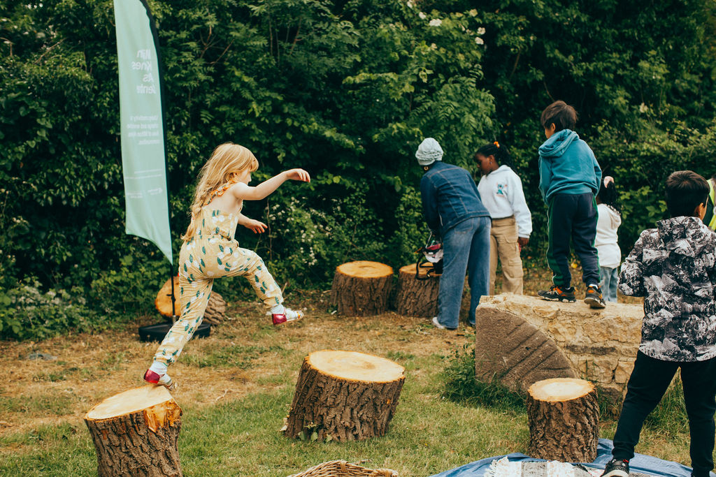 Children playfully leaping from sawn logs and mill stones on the grounds outside of the Bradwell WIndmill.