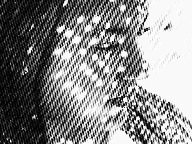 Black and white close-up of a person’s face with light dots creating a pattern across the skin, eyes closed.