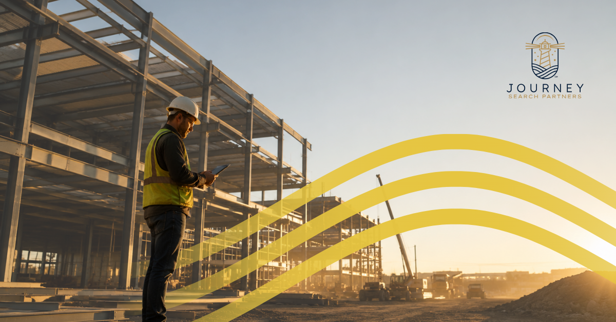 A construction worker in a hard hat and safety vest reviewing plans on a tablet at a steel-frame building site, representing the technical roles firms struggle to fill.