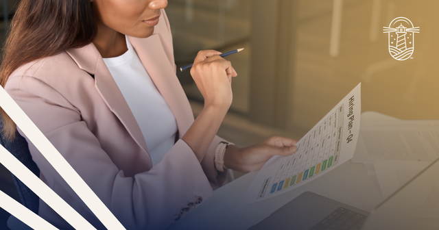 A woman holding a pencil reviews a printed “Hiring Plan – Q4” spreadsheet at her desk. Journey Search Partners logo.