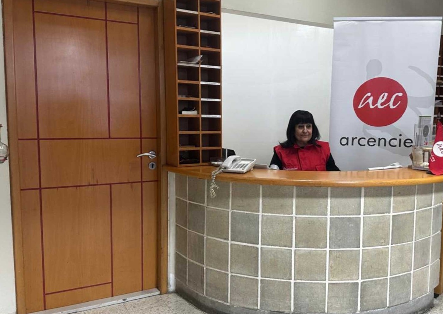 An arcenciel staff member wearing a red vest delivers a wheelchair and essential supplies in a residential area.
