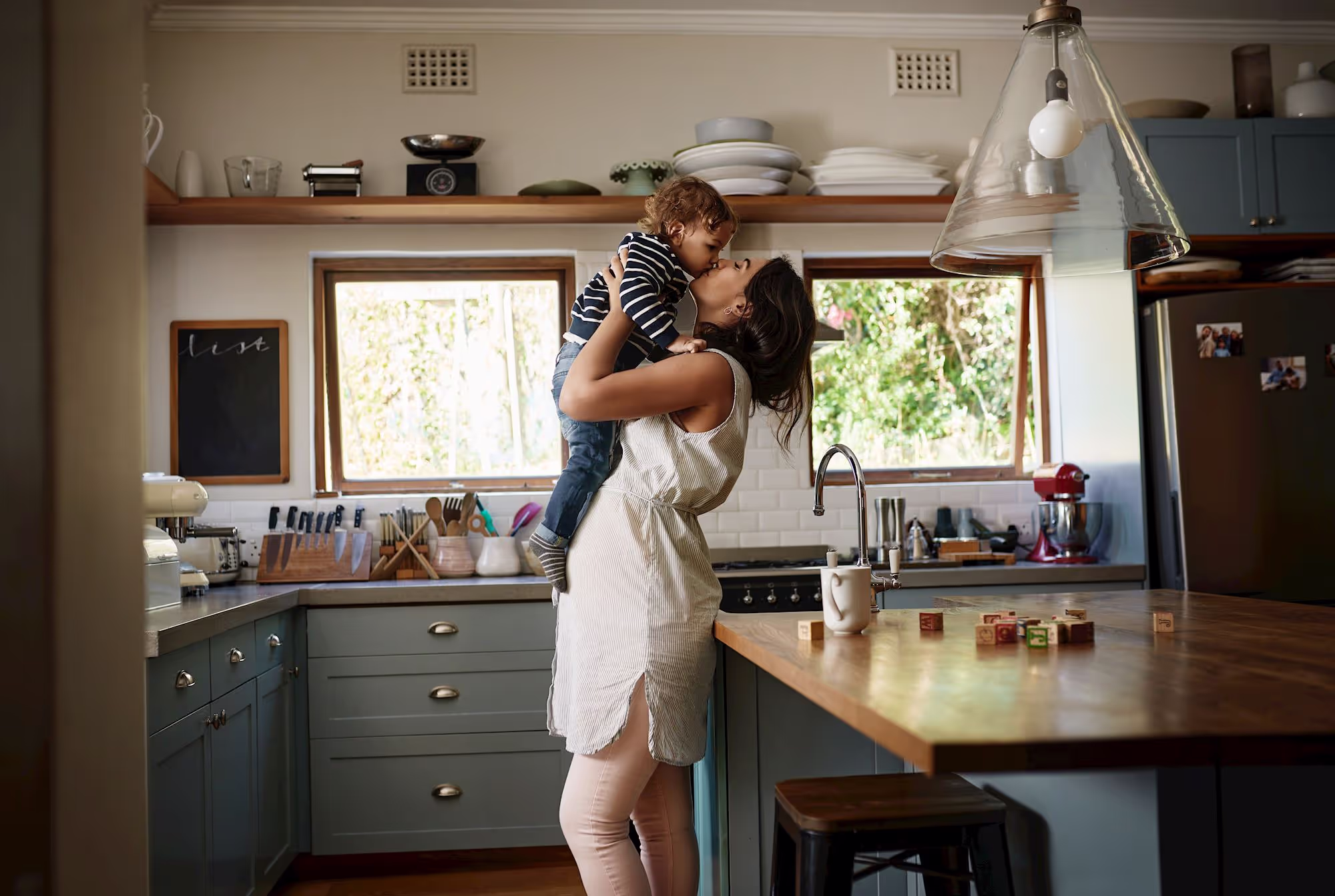 A mother embracing her child in their kitchen at home