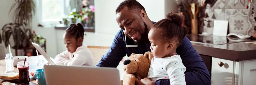 Father sitting with child on his laptop, on the phone, reading his computer