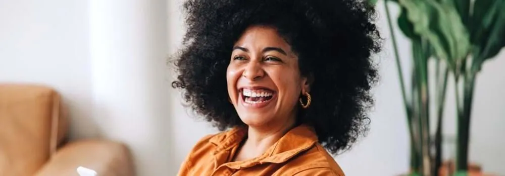 Woman sitting in her lounge room smiling