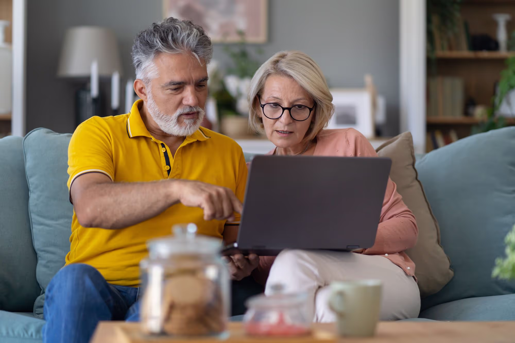 Couple sitting on the couch reading laptop