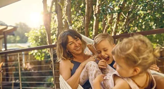 Woman smiling in hammock with her kids